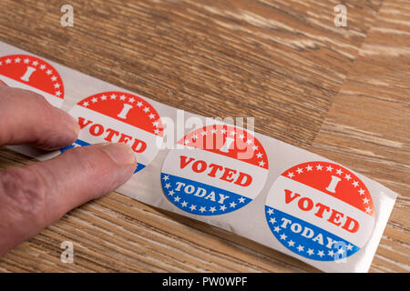 Roll of I Voted Today paper stickers on table with senior man hand Stock Photo