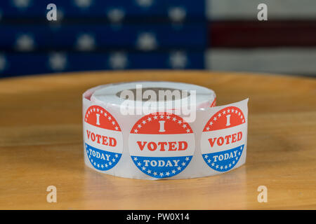 Roll of I Voted Today paper stickers on table with US Flag in background Stock Photo