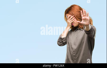 Young beautiful woman over isolated background covering eyes with hands and doing stop gesture with sad and fear expression. Embarrassed and negative  Stock Photo