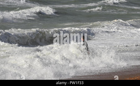 Brighton UK 12th October 2018 - A kite surfer braves the huge waves off Brighton beach today in high winds as Storm Callum sweeps across parts of Britain today Credit: Simon Dack/Alamy Live News Stock Photo