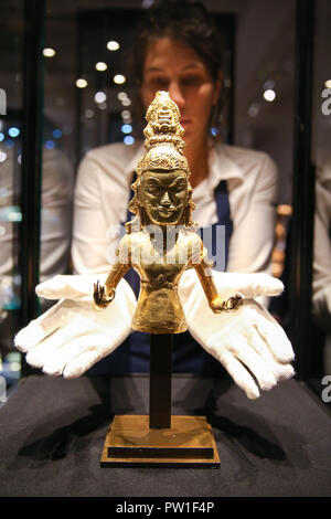 London Sotheby's. London. UK 12 Oct 2018 - A technician holds Late 7th / early 8th Century gold figure of the Bodhisattva Avalokiteshvara (est £80,000 - £100,000)  'The Midas Touch' Auction Dedicated to Gold at London Sotheby's photocall alongside fascinating pieces of Jewellery, Fine Art and Decorative Arts telling the story of the single metal that has seduced, obsessed and intoxicated mankind for over six millennia. Auction in London Sotheby's on 17 October 2018.   Credit: Dinendra Haria/Alamy Live News Stock Photo