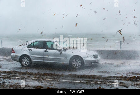 Penzance, Cornwall, UK. 12th October 2018. UK Weather. Storm Callum hits Penzance sea front, and brings huge waves crashing over the paths and roads. This car parked on the seafront was getting covered in seaweed and debris brought up by the sea Credit: Simon Maycock/Alamy Live News Stock Photo