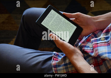 Man reading ebook on his electronic books reader. Stock Photo