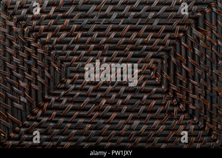 Natural texture of braided wicker of dark color. Horizontal and vertical lines. Ocher, brown and black tones. Stock Photo