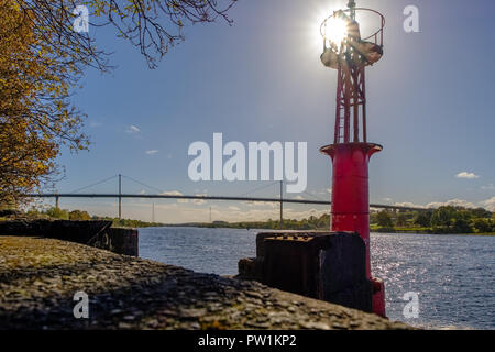 Old Port Beacon on the River Clyde with Erskine Bridge in the Background and the sun behind the Beacon. Stock Photo