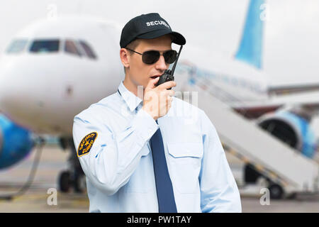 Portrait Of A Male Security Guard Talking On Walkie Talkie At An Airport Stock Photo