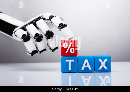 Robot Finger Touching Percentage Sign Over Tax Block Against Gray Background Stock Photo