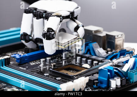 Close-up Of A Robotic Hand Placing Processor Chip In Motherboard Stock Photo