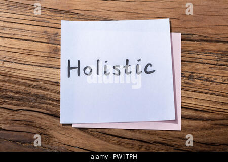Elevated View Of Holistic Word On Adhesive Note Over Wooden Background Stock Photo
