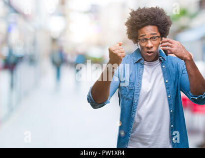 Afro american man talking on the phone over isolated background annoyed and frustrated shouting with anger, crazy and yelling with raised hand, anger  Stock Photo