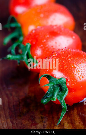 macro images of four wet tomatoes closeup on wooden table Stock Photo