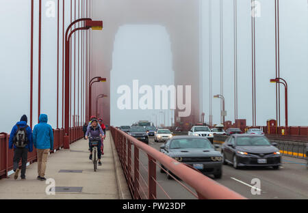 Pedestrians, bikers and a tour bus on the Golden Gate Bridge San Francisco, California, United States, on a late foggy summer morning. Stock Photo