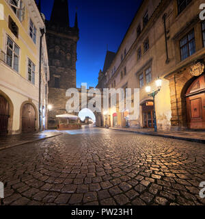Medieval street leading towards Lesser Town Bridge Tower towards Charles Bridge on a rainy night in Prague, Czech Republic Stock Photo