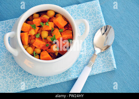 Homemade chickpea sweet potato curry in white bowl with on pale blue background.  Horizontal format shot in natural light. Stock Photo