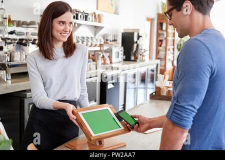 Male customer makes payment by smartphone at a coffee shop Stock Photo