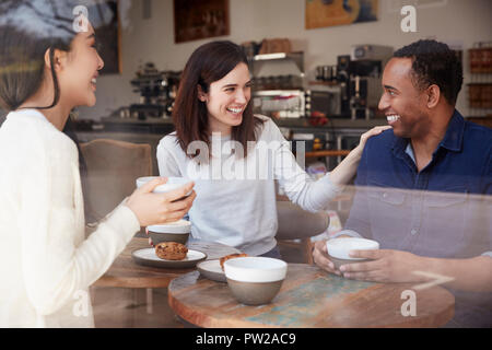 Three friends having coffee and laughing at a coffee shop Stock Photo