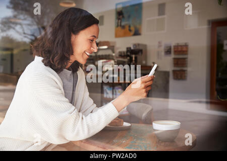 Young woman using her smartphone at a coffee shop Stock Photo