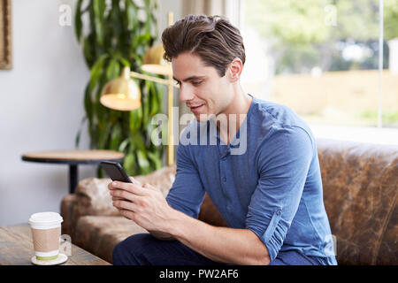 Young Caucasian man using smartphone in a coffee shop Stock Photo