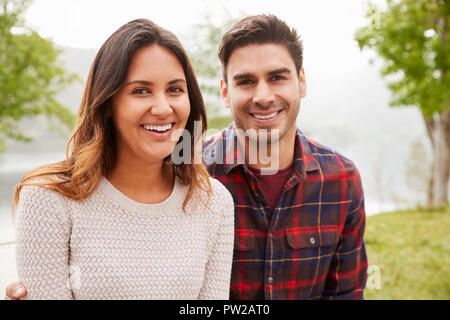 Young smiling couple sitting a park, portrait Stock Photo