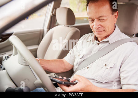 Senior man in car using his smartphone while driving Stock Photo