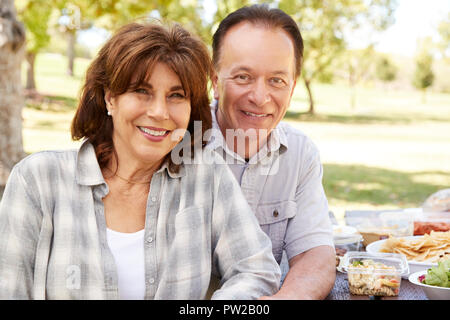 Senior couple sitting at picnic table in a park Stock Photo