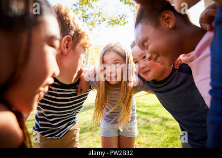 Multi-ethnic group of kids embracing, looking at each other Stock Photo