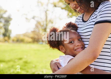 Portrait Of Mother Hugging Daughter In Park Stock Photo
