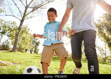 Father And Son Playing Soccer In Park Together Stock Photo
