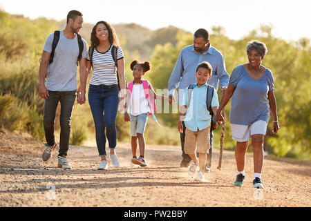 Multi Generation Family Wearing Backpacks Hiking In Countryside Together Stock Photo