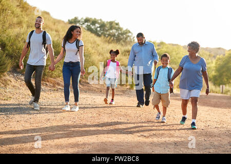 Multi Generation Family Wearing Backpacks Hiking In Countryside Together Stock Photo