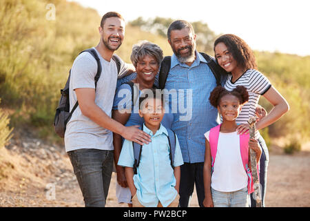 Portrait Of Multi Generation Family Wearing Backpacks Hiking In Countryside Together Stock Photo