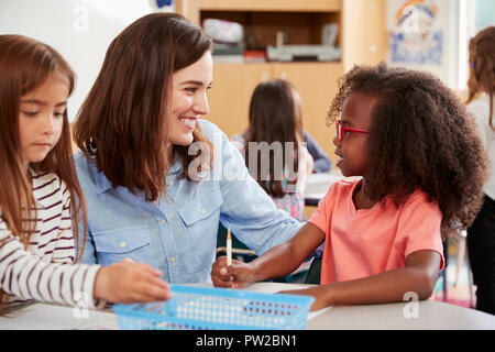 Female primary school teacher and girls in class, close up Stock Photo