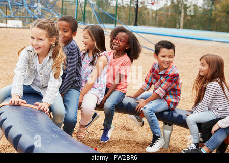 Kids sitting on a spinning carousel in their schoolyard Stock Photo