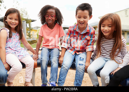 Kids sitting on a spinning carousel in their schoolyard Stock Photo