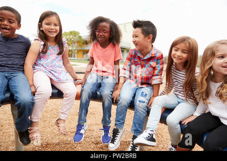 Elementary school friends sitting on a spinning carousel Stock Photo