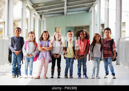 Elementary school kids stand in corridor looking at camera Stock Photo