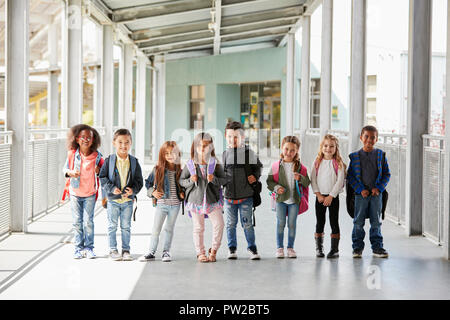 Elementary school class standing in corridor with their bags Stock Photo