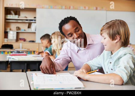 Male elementary school teacher and boy in class, close up Stock Photo