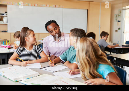 Teacher working with elementary school kids at their desk Stock Photo