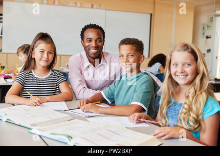 Male school teacher and kids in class smiling to camera Stock Photo