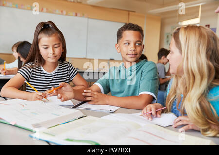 Elementary school kids in class working together at a desk Stock Photo