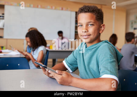 Boy using tablet in school class smiling to camera, close up Stock Photo
