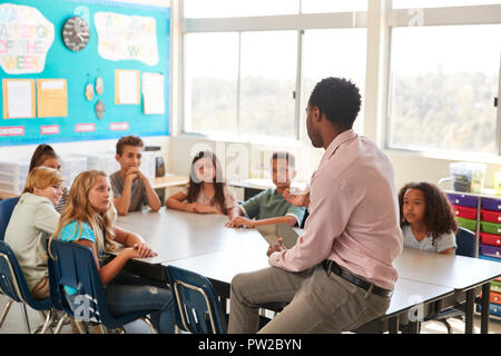 Male teacher with elementary school kids in class discussion Stock Photo