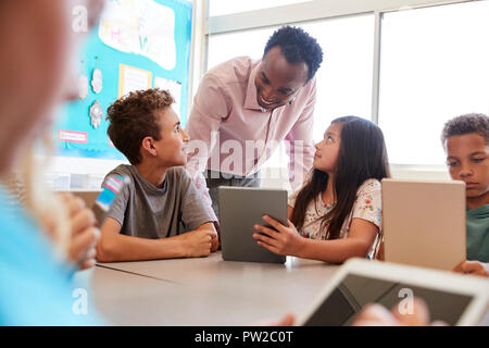 Teacher among kids with computers in elementary school class Stock Photo