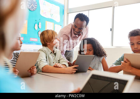 Teacher among kids with computers in elementary school class Stock Photo