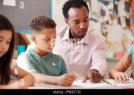 Male teacher working with schoolboy at desk, close up Stock Photo