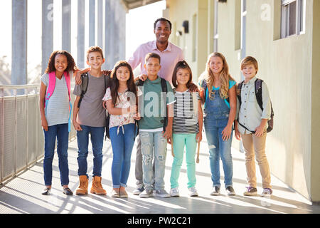 Elementary school teacher and his pupils in school corridor Stock Photo