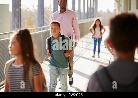 Male teacher and pupils walking in school campus Stock Photo