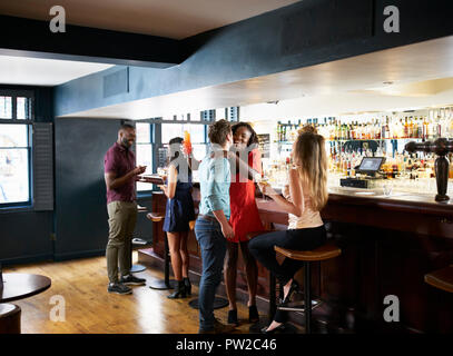 Group Of Young Friends Relaxing In Bar Standing At Counter Stock Photo