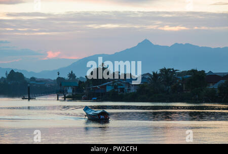 Boat floating on a river in Kuching during sunset Stock Photo